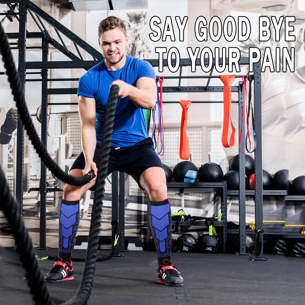 A muscular man exercises with a black cable machine and various fitness equipment, wearing blue compression socks.