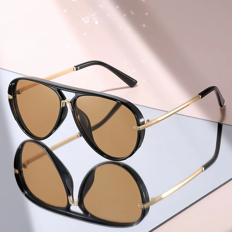 A pair of classic gradient aviator sunglasses with black frames and gold accents displayed on a light surface.