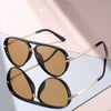 A pair of classic gradient aviator sunglasses with black frames and gold accents displayed on a light surface.