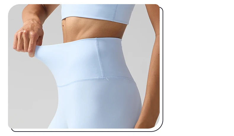 Une femme porte des leggings de performance bleu clair taille haute, de la taille vers le bas.