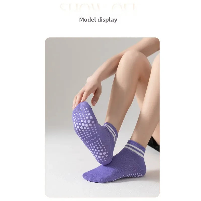 A model is wearing purple non-slip grip socks for yoga or pilates on their foot.