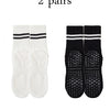 Two pairs of black grip socks with white stripes and two pairs of white socks with black stripes