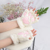 Pair of white plush cat claw mittens with pink paw prints resting on a white surface.