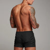 A man wearing black stretch performance drawstring shorts, shown from the back.