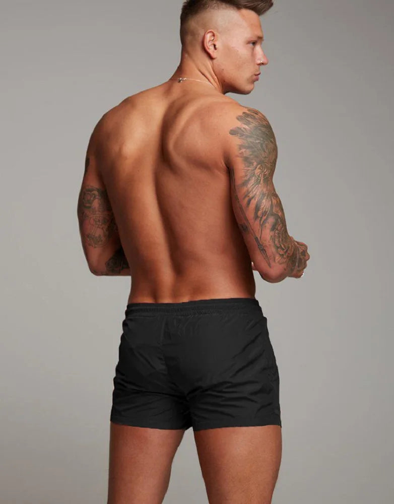 A man wearing black stretch performance drawstring shorts, shown from the back.