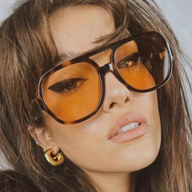 Primer plano de una mujer usando gafas de sol cuadradas y ligeras con tinte naranja.