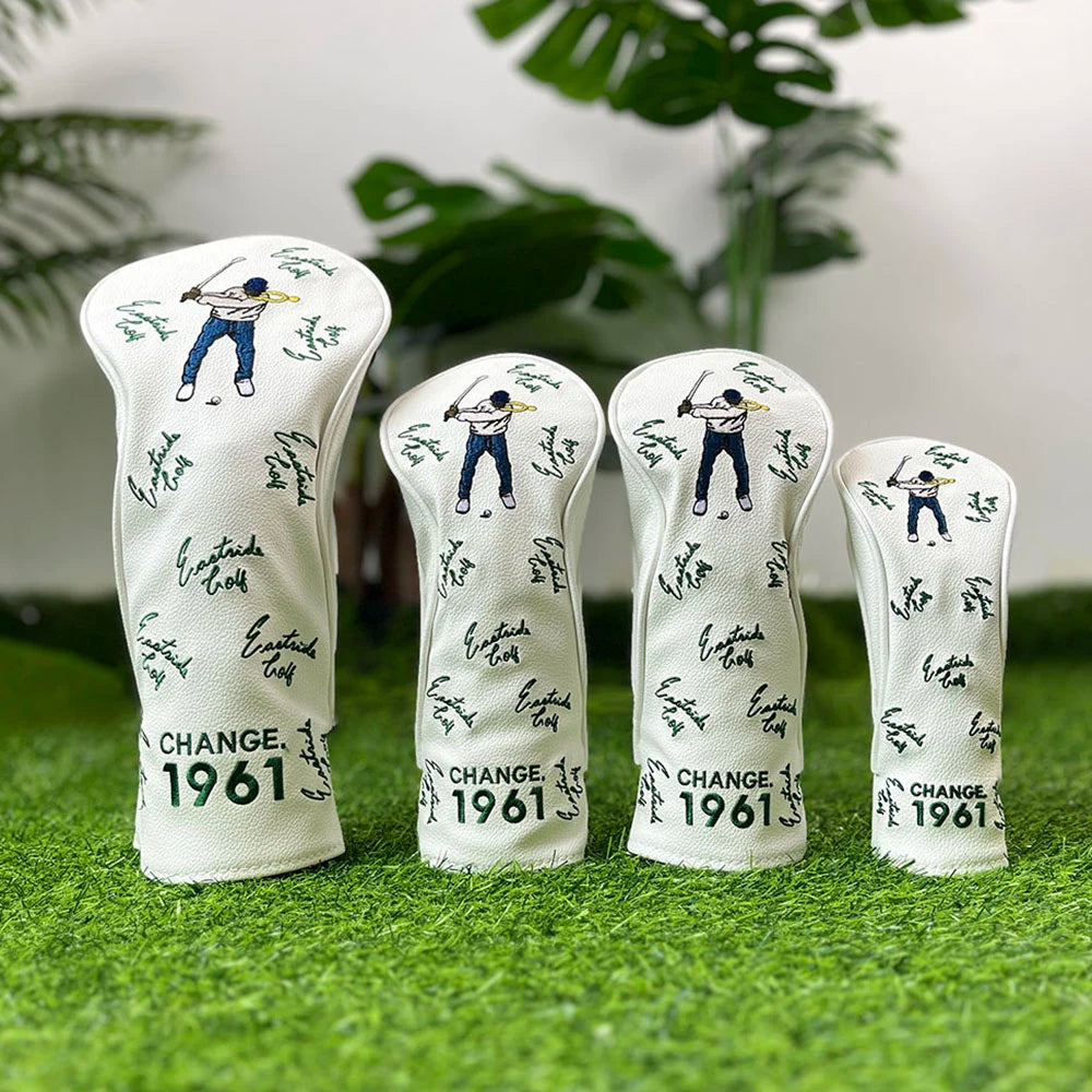 A set of four white golf club head covers featuring a silhouette of a golfer and the text CHANGE 1961 on a green surface.