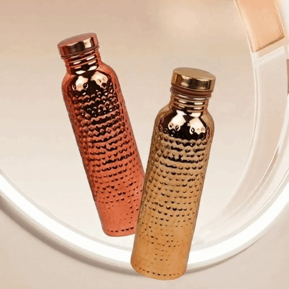 A close-up view of an insulated copper water bottle with a textured anti-slip grip set against a light background.