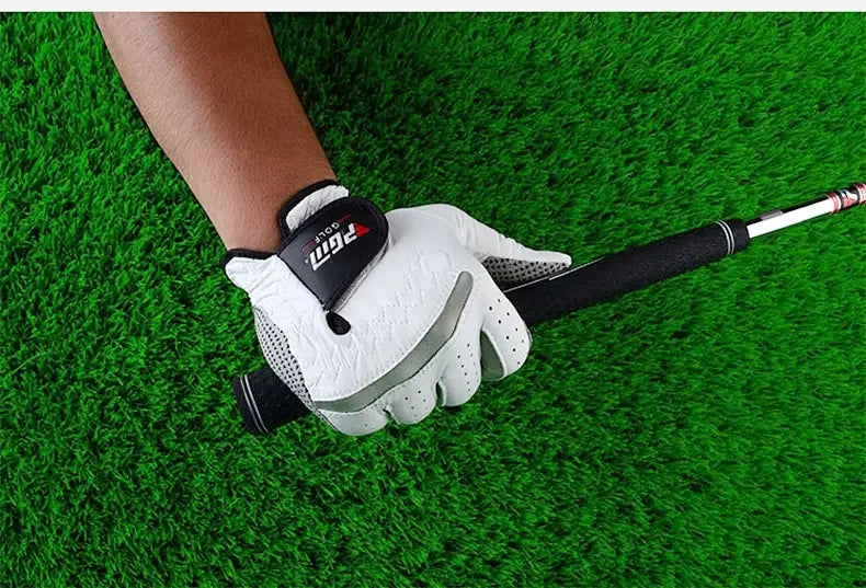 A hand wearing a white golf glove with black accents is holding a golf club on a green turf.
