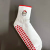 Weiße Strick-Yoga- und Fitnesssocken mit rohem Bund und einem Muster aus roten Herzen am Fuß.