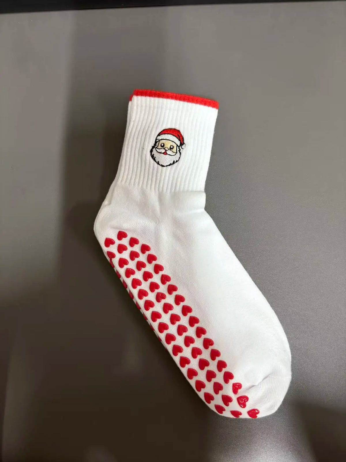 Weiße Strick-Yoga- und Fitnesssocken mit rohem Bund und einem Muster aus roten Herzen am Fuß.