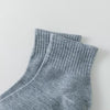 Ein Stapel grauer, atmungsaktiver Baumwoll-Socken für Herren, präsentiert vor weißem Hintergrund.