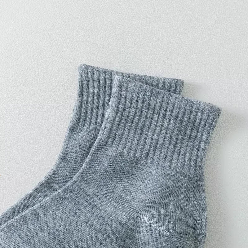 Ein Stapel grauer, atmungsaktiver Baumwoll-Socken für Herren, präsentiert vor weißem Hintergrund.