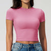 Una modelo vistiendo una camiseta deportiva de yoga y fitness rosa y jeans de mezclilla.