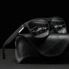 Vintage designer square sunglasses resting on a black leather surface with a blurred car in the background.