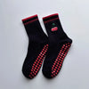 Paire de chaussettes de yoga noires avec broderie rouge et ourlet rose