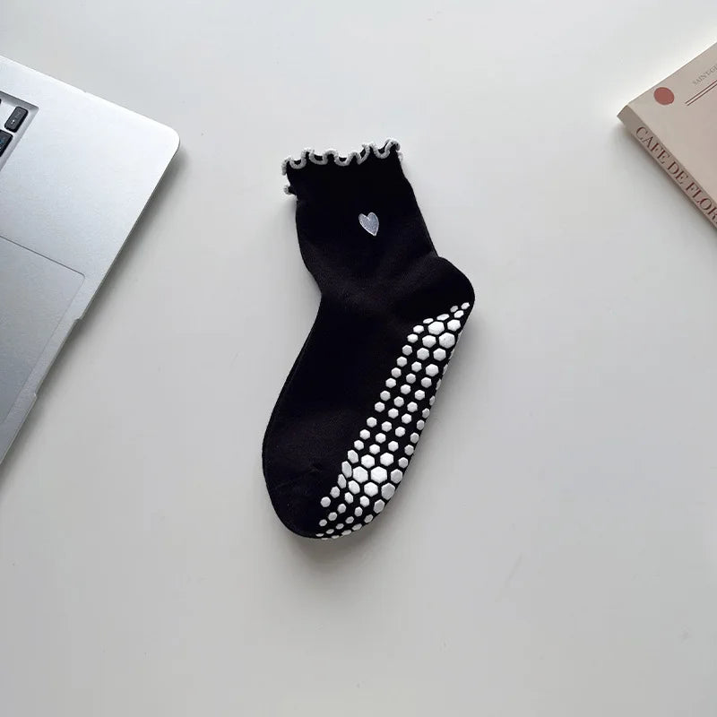 Black yoga socks with silver embroidery and white polka dots resting on a white surface.