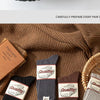 A stack of thick cotton tube socks in various colors and textures resting on a brown knitted fabric.