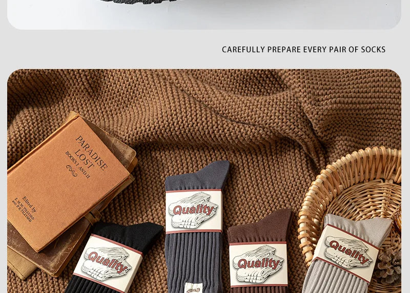 A stack of thick cotton tube socks in various colors and textures resting on a brown knitted fabric.