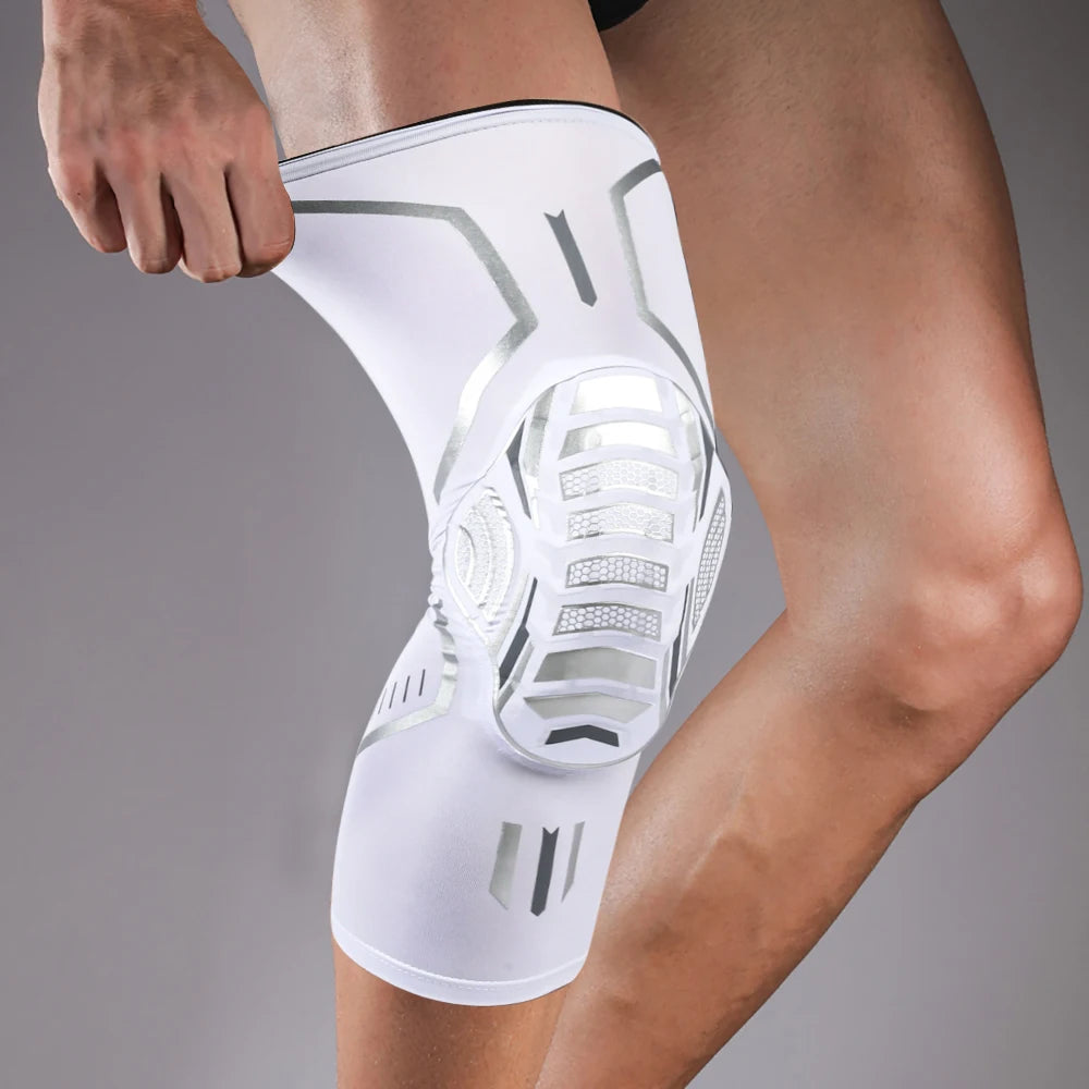 A white compression knee brace with metallic accents is worn on a person's leg.