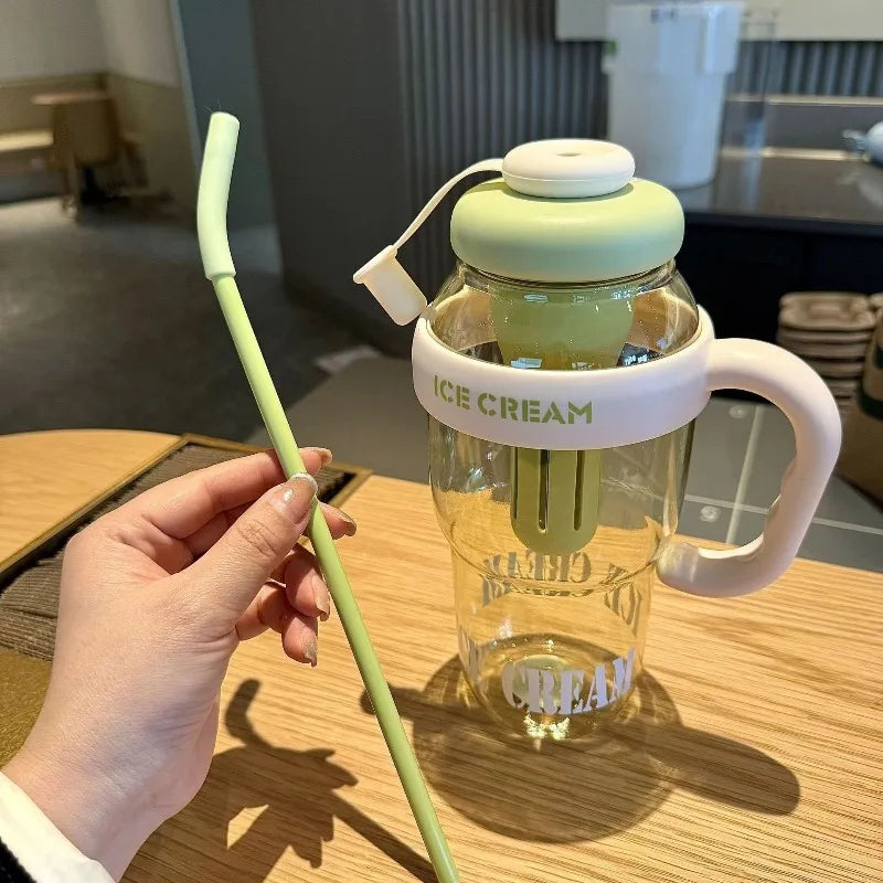 A hand holds a large capacity plastic sports water bottle with a straw and lid, filled with ice cream.