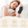 A woman is shown resting her arm on a pillow while wearing a black adjustable wrist support brace.