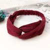 A maroon ribbed fabric headband or hair accessory lying on a white surface.