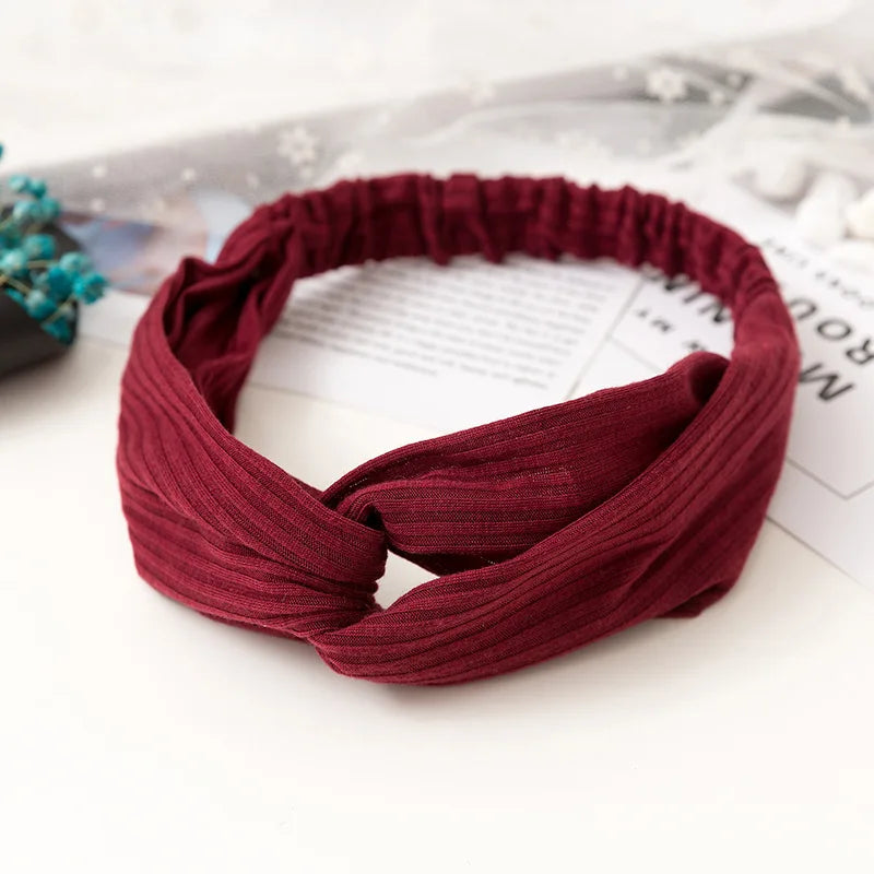 A maroon ribbed fabric headband or hair accessory lying on a white surface.