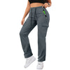 A woman wearing gray drawstring cargo pants and a black top, standing and looking down.