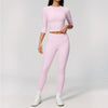 A woman wearing a light pink yoga and fitness leggings set consisting of a long-sleeved top and matching pants.