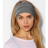 Una mujer rubia modela una diadema ancha bohemia gris para peinar el cabello.