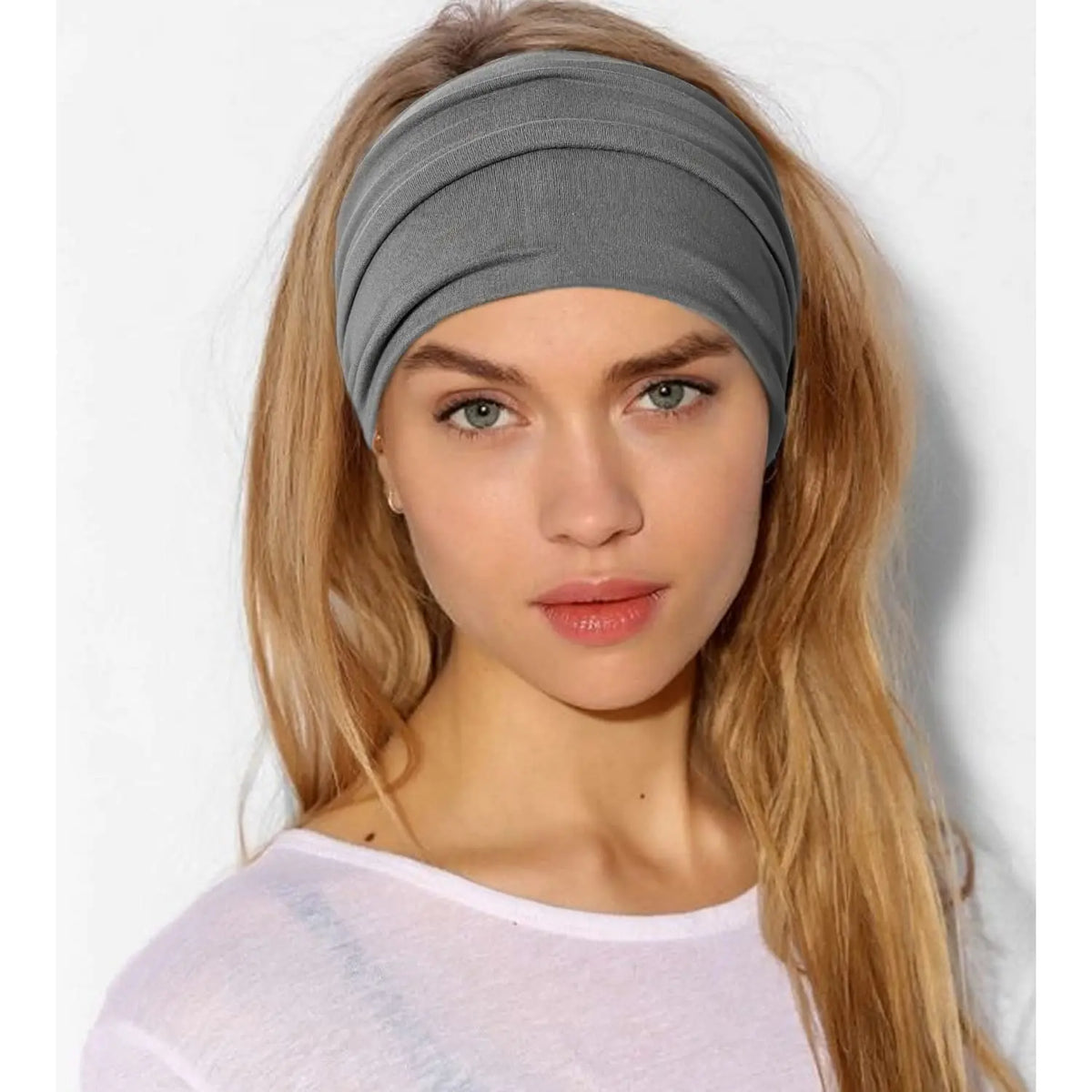 Una mujer rubia modela una diadema ancha bohemia gris para peinar el cabello.