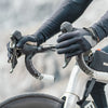 A close-up of a person wearing black cycling gloves gripping the handlebars of a bicycle.