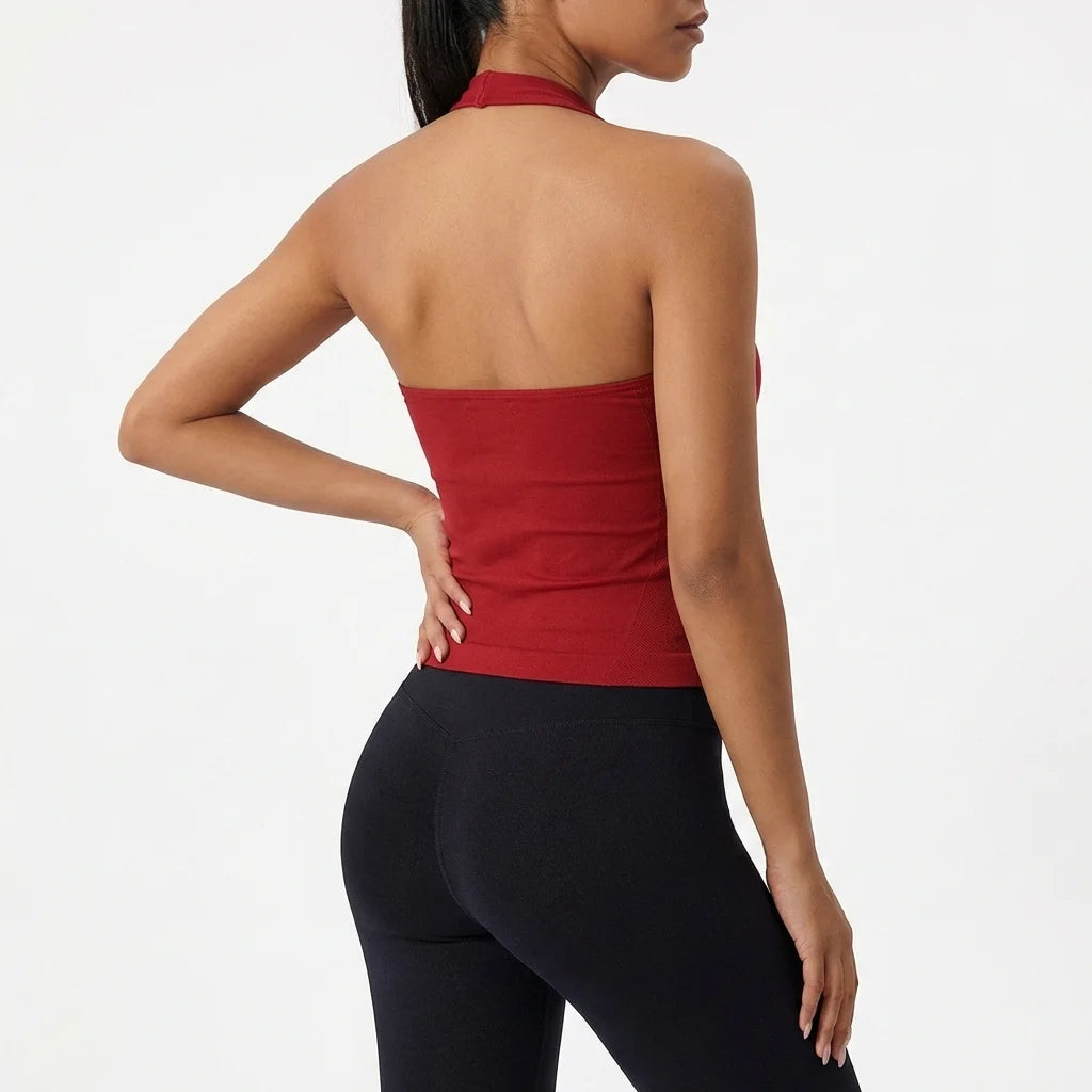 A woman wearing a red seamless yoga sports bra and black leggings, shown from the back.