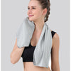 A woman wearing a black sports bra and shorts is demonstrating an instant cooling towel for sports and fitness.