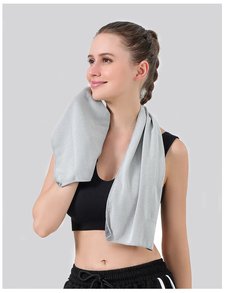 A woman wearing a black sports bra and shorts is demonstrating an instant cooling towel for sports and fitness.