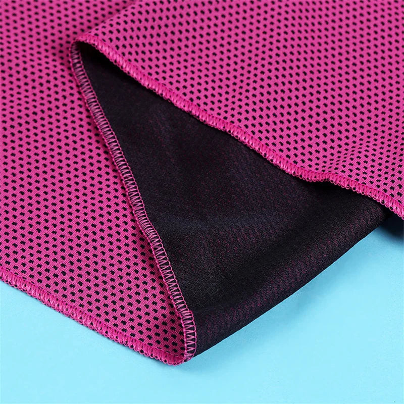 A close-up of a magenta microfiber cooling towel folded, showing the textured fabric and a dark purple lining.