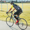 A cyclist wearing a black and yellow jersey rides a bicycle on a paved road.