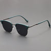 Vintage square metal frame sunglasses in a muted green color resting on a gray surface.