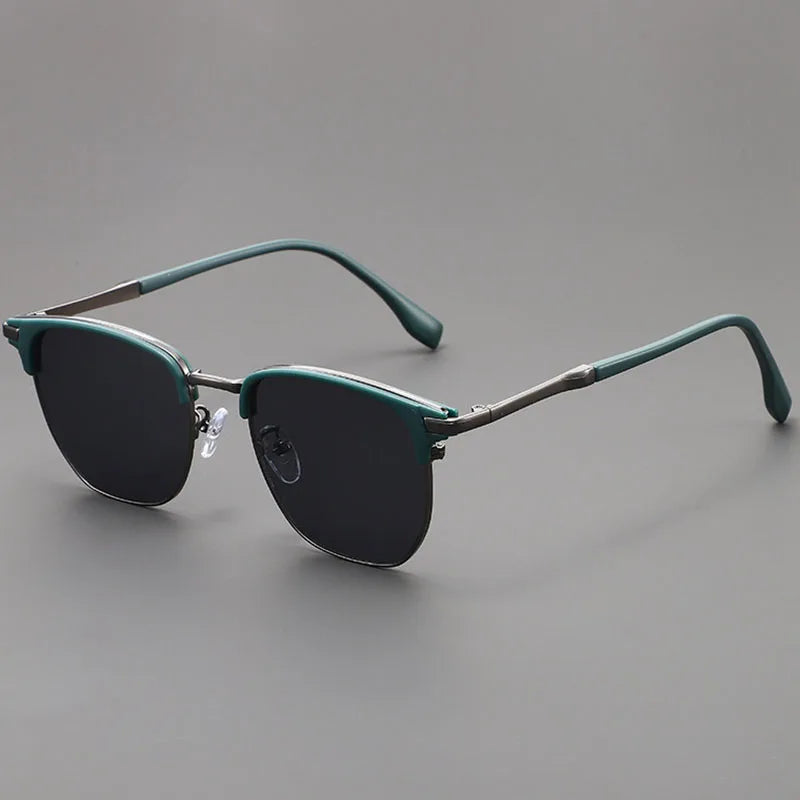 Vintage square metal frame sunglasses in a muted green color resting on a gray surface.