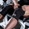 A person wearing black neoprene knee pads while exercising or lifting weights.