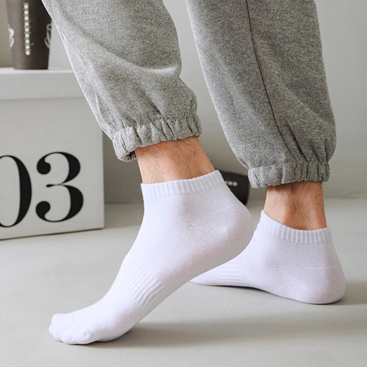A close-up shot of a person's legs and feet wearing white thin ankle socks.