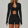 Eine Frau modelliert ein schwarzes, nahtloses Sport-Yoga-Set mit Zip-Front-Top und passenden Shorts.