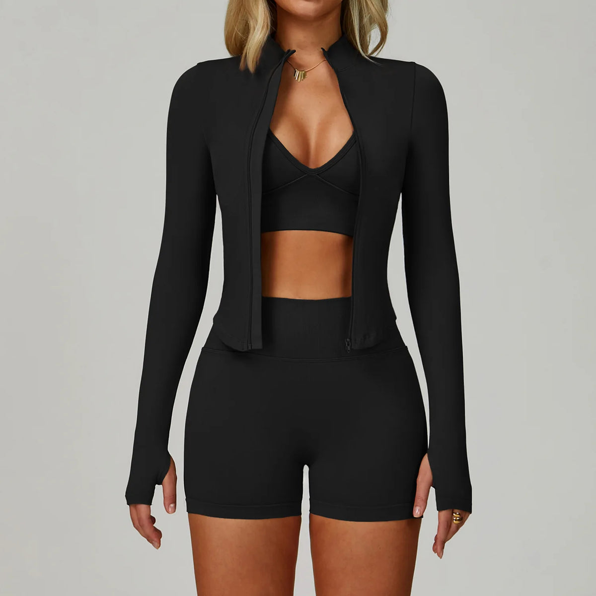 Eine Frau modelliert ein schwarzes, nahtloses Sport-Yoga-Set mit Zip-Front-Top und passenden Shorts.