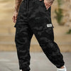 Un homme portant un pantalon cargo camouflage noir et des baskets blanches, montrant la coupe du pantalon.