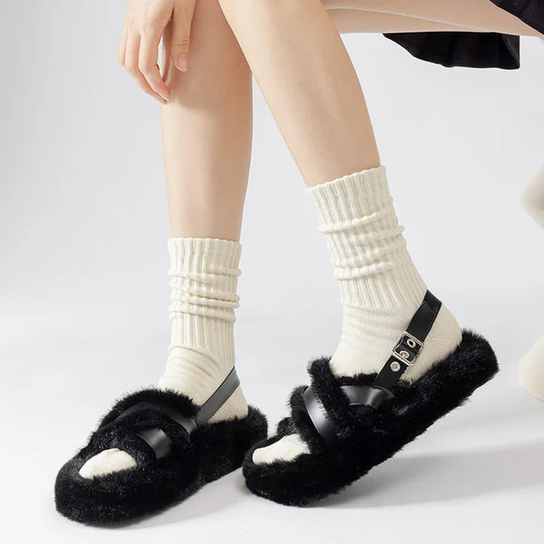 A pair of thick white cotton tube socks worn with black slides and fuzzy black slippers.