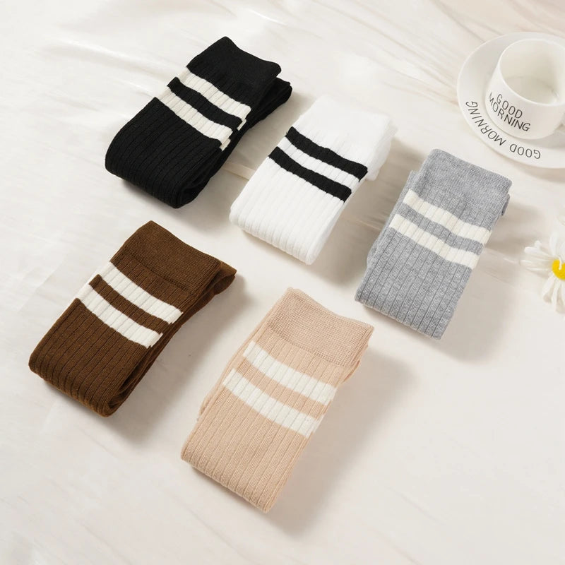 A collection of women's striped cotton knee high socks in black, white, and brown tones arranged on a white surface.