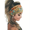 A woman wearing a floral butterfly patterned headband in orange and teal on her forehead.