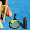 A person is holding a tennis racket and a yellow tennis ball on a blue court with an insulated water bottle nearby.