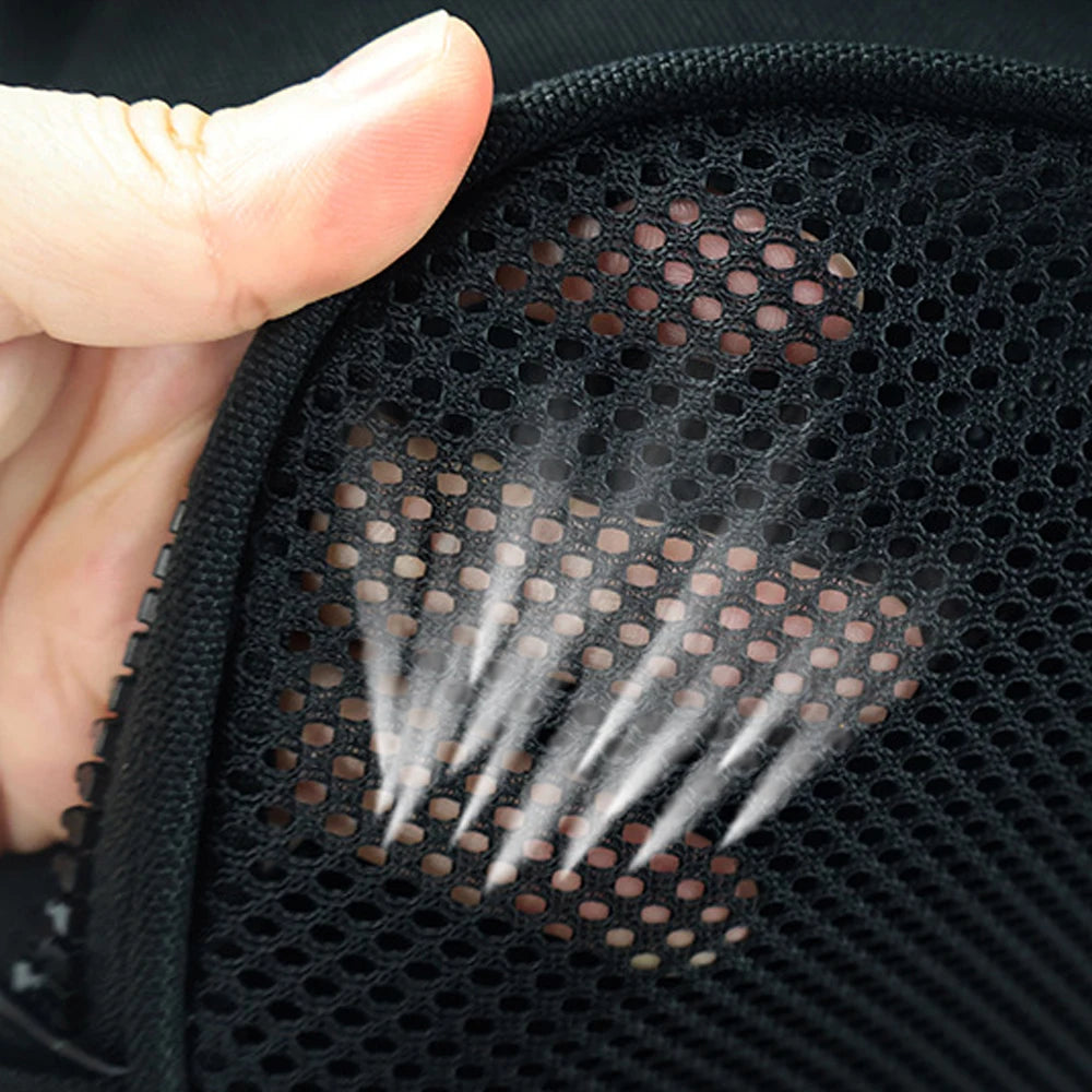 A hand is demonstrating the mesh opening of a black waterproof sports shoe carrier bag, showing water spray.